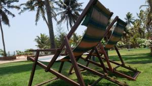 2 tumbonas en un parque con palmeras en Villa Malpe, en Udupi