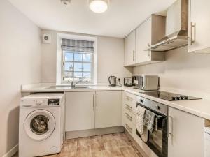 Una cocina blanca con lavadora y secadora. en Inverkeithing View - Uk38588, en Inverkeithing