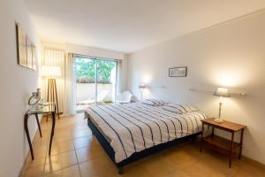 1 dormitorio con cama y ventana grande en Forest flat / Terrasse-spa-bbq-10min à pieds de la plage, en La Teste-de-Buch