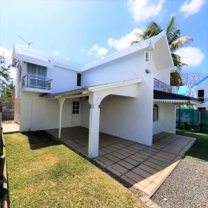 a white house with a balcony and a yard at Villa Rose in Pereybere