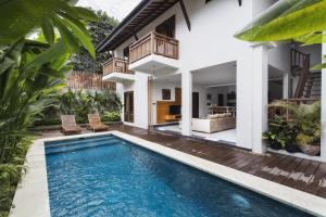 a villa with a swimming pool in front of a house at Delu Villas & Suite in Kerobokan