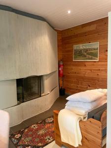 1 dormitorio con chimenea en una pared de madera en Katiskosken joenrantamökki, en Hämeenlinna