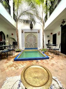 Habitación con piscina con mesa y palmeras en Dar Fangui, en Marrakech