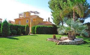 una casa amarilla con una palmera en un patio en El Paraiso Residence Club Mallorca, en Sa Ràpita