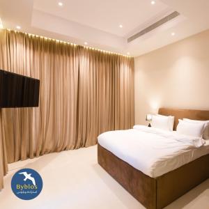 a bedroom with a large bed in front of a window at Byblos Villa Resort in Al Ḩadd