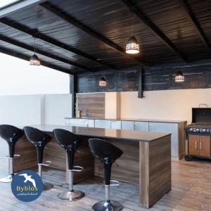 a kitchen with a wooden table and black stools at Byblos Villa Resort in Al Ḩadd