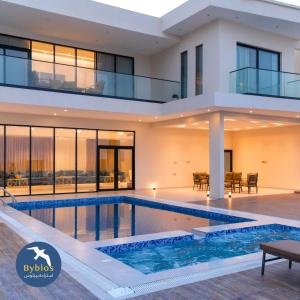 a house with a swimming pool in front of it at Byblos Villa Resort in Al Ḩadd