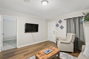 a living room with a tv and a chair and a table at Unit 19 Green Acres Apartment in Enterprise