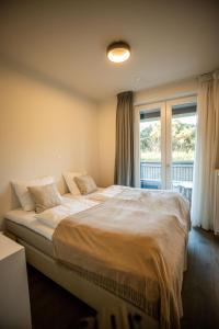 a bedroom with a large bed in front of a window at The Lagune, light and sunny apartment in the dunes in Cadzand