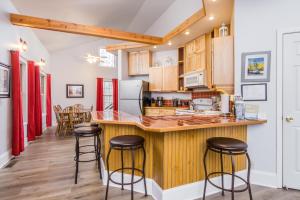 a kitchen with wooden cabinets and bar stools at New Listing! Bavarian Cabin - 2 Bedrooms, 8 Minutes to Dahlonega, Hot Tub, Game Room in Dahlonega