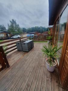 una terraza de madera con mesa y plantas. en Chillingham lodge with hot tub Felmoor Park, en Felton