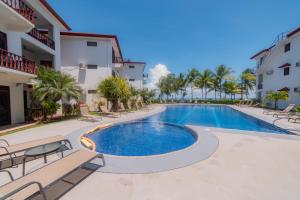 a swimming pool in a resort with chairs and palm trees at Delluz Bahia Azul 4B Pool view, Jaco Beach 2nd floor in Jacó