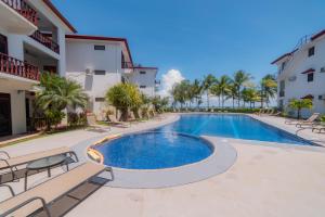 a swimming pool in a resort with chairs and palm trees at Bahia Azul 2A beachfront, Jaco Beach, 1st floor in Jacó