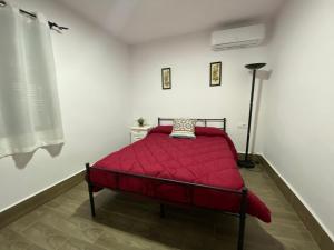 Cama roja en habitación blanca con lámpara en El Galindón Rancho, en La Puebla de los Infantes