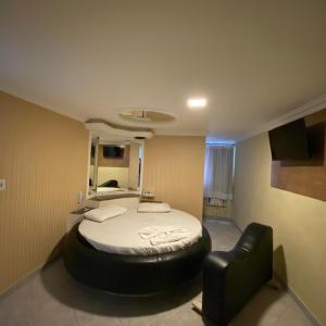 a bedroom with a bed and a black leather chair at Hotel Milenium Itapuã in Salvador