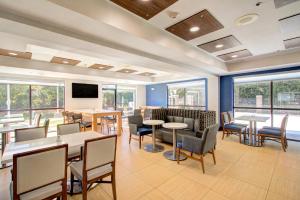 a dining room with tables and chairs and windows at Holiday Inn Express & Suites Charlotte-Concord-I-85 by IHG in Concord