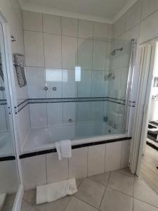 a bathroom with a tub and a glass shower at On the Rocks Guesthouse in Gansbaai