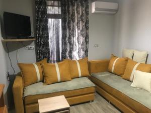 ein Wohnzimmer mit einem Sofa und einem TV in der Unterkunft JANO apartment Korce in Korçë