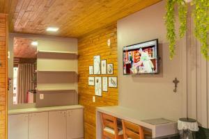 Una sala de estar con un televisor en la pared. en POUSADA 05 LUAS URUBICI, en Urubici
