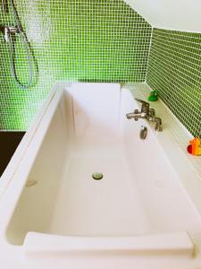 La salle de bains carrelée de couleur verte est pourvue d'une baignoire blanche. dans l'établissement Maisonnette du coteau ouest - Jardin et terrasse - Epernay, à Épernay
