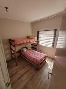 a small room with two bunk beds and a window at Hermosa casa en Bahía inglesa 3 habitaciones in Bahia Inglesa