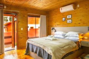 a bedroom with a bed in a room with wooden walls at POUSADA 05 LUAS URUBICI in Urubici