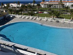 a large swimming pool with chairs and a building at Playa del Duque-Amazing views 2 bedroom in Adeje