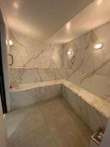 a bathroom with white marble walls and a tub at Apto c/ piscina e vista para o mar - Caraguatatuba in Caraguatatuba