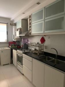 una cocina con armarios blancos y fregadero en “Tu Lugar en Santiago” Depto SADIMA - Barrio Centro en Santiago del Estero