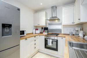 uma cozinha com armários brancos e um lavatório em MPL Apartments - Queens Broadway F3 em Watford