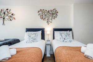 two beds in a room with a heart on the wall at MPL Apartments - Queens Broadway F3 in Watford