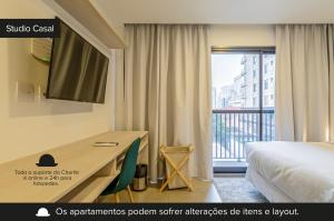 um quarto de hotel com uma secretária, uma cama e uma janela em Charlie Sabiá Moema em São Paulo
