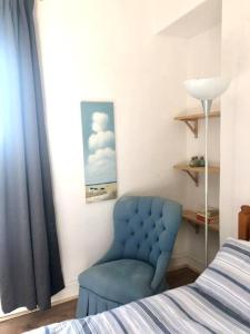 een slaapkamer met een blauwe stoel naast een bed bij City living maisonette, The Nest in Swansea
