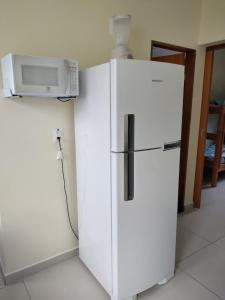 a white refrigerator with a microwave on top of it at Canto Verde Aptos II in Caraguatatuba