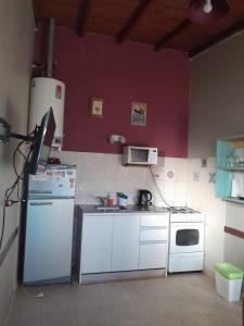 kuchnia z białymi urządzeniami i fioletową ścianą w obiekcie Casa en Necochea w mieście Necochea