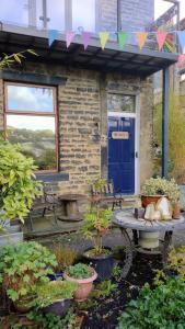 ein Haus mit einer blauen Tür und einigen Topfpflanzen in der Unterkunft The Cabin: Great Views,Garden,Close to Town, Quiet in Hebden Bridge
