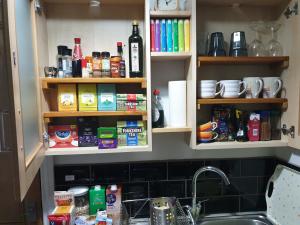 a kitchen with a sink and some shelves with food at The Cabin: Great Views,Garden,Close to Town, Quiet in Hebden Bridge