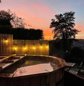 a backyard swimming pool with a fence and a sunset at Secluded lodge with spectacular views and hot tub! in Bath