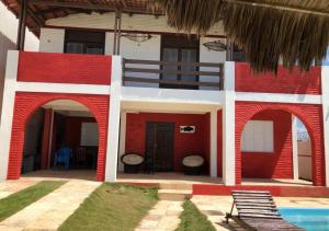 un edificio rojo y blanco con piscina en CASA DE PRAIA (PE NA AREIA), en Caponga