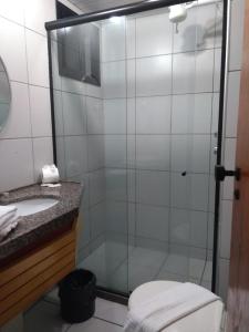 a glass shower in a bathroom with a sink at Ocean Tower Fortaleza in Fortaleza