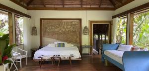 ein Schlafzimmer mit einem Bett, einem Sofa und Fenstern in der Unterkunft Pacuare Lodge by Böëna in Bajo Tigre