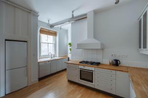 倫敦的住宿－Bright Space in the Heart of London，厨房配有白色橱柜和炉灶烤箱。