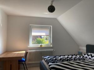 Un dormitorio con una cama y un escritorio y una ventana. en Casa Bianca, en Fehmarn
