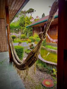 a hammock hanging from a building in a garden at Pousada Recanto Ninho Verde Chalés in Campos do Jordão