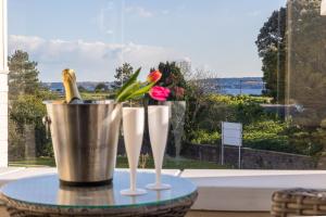 a table with two champagne glasses and a bucket at Rutland Heights,A Fantastic Modern Coastal House, Sea Views, Garden, Terraces, 2x Allocated Private Parking Spaces plus Free Private use of Electric Vehicle Point Meadfoot Beach only 5mins away! Also Shops, Bars and Restaurants just a 10 minute walk! in Torquay