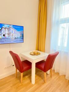 a white table with two red chairs and a tv at Steiner Residences Vienna Reumannplatz in Vienna