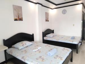 Dos camas en una habitación con paredes blancas. en Strangers Inn&Bar, en General Luna