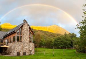 a rainbow over a stone house in a field at Strath Lodge Glencoe in Glencoe
