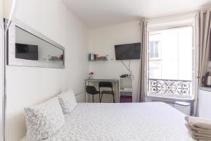 una camera bianca con letto e scrivania di RASPAIL Cozy Flat a Parigi