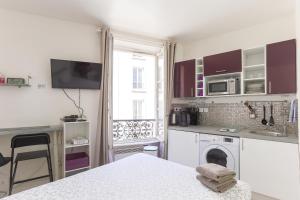 - une cuisine blanche avec un évier et une table dans l'établissement RASPAIL Cozy Flat, à Paris